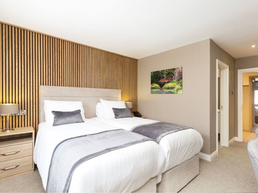 Una habitación de hotel moderna con una cama grande, mesitas de noche, una lámpara y un cuadro en la pared.