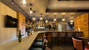 A bar area with a brick wall, multiple hanging lights, and bar stools. - Castle Varagh Hotel & Bar (Castlepollard)