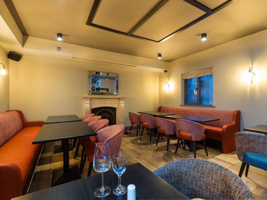 A restaurant with a fireplace, orange seating, and tables.