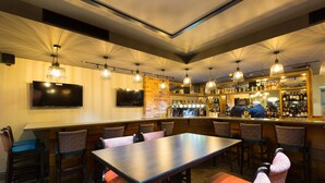 A bar area with a long counter, multiple bar stools, and a television mounted on the wall. - Castle Varagh Hotel & Bar (Castlepollard)