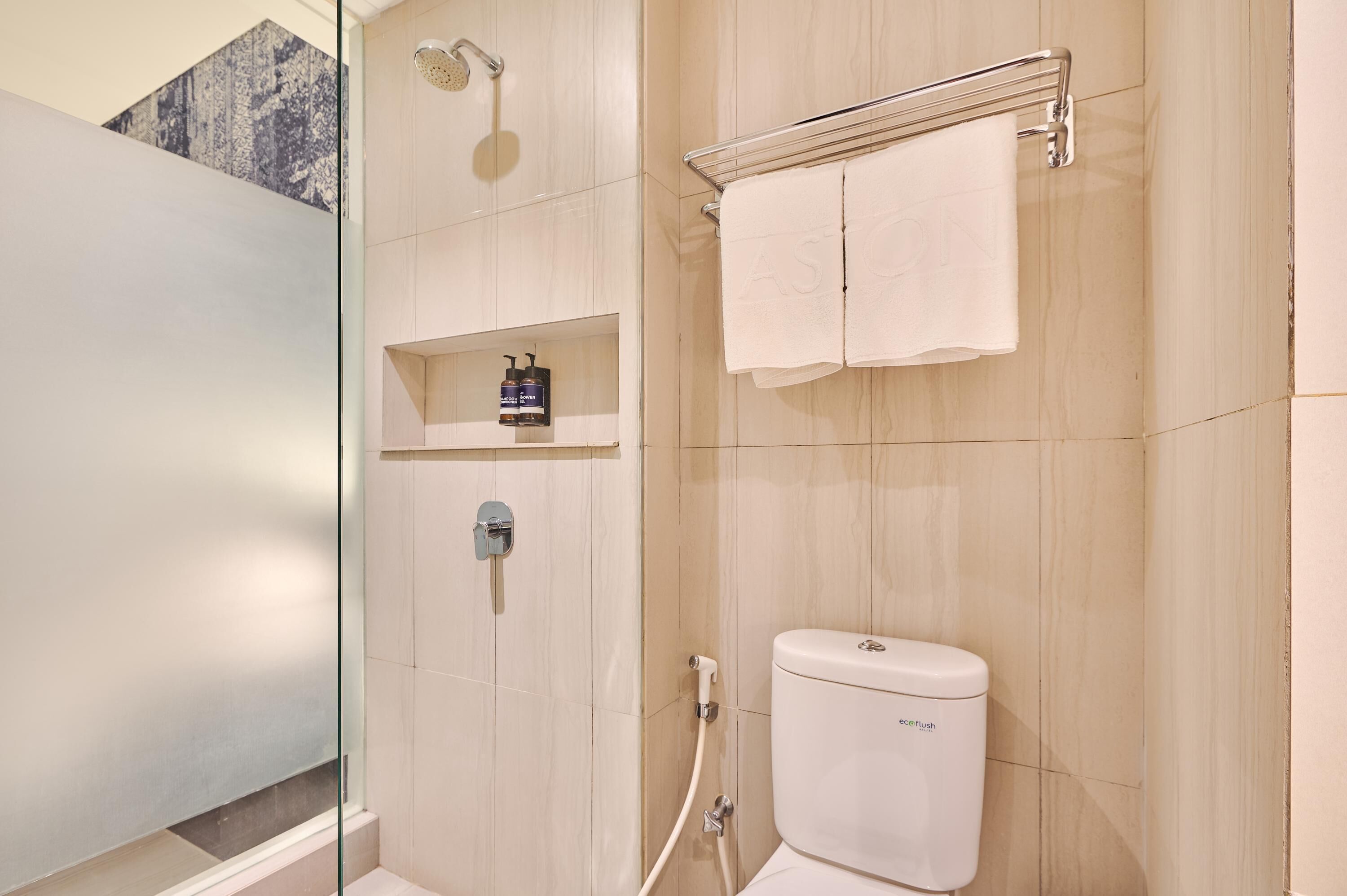 Ein modernes Badezimmer mit Duschkabine aus Glas, Toilette und Ablage für Toilettenartikel.