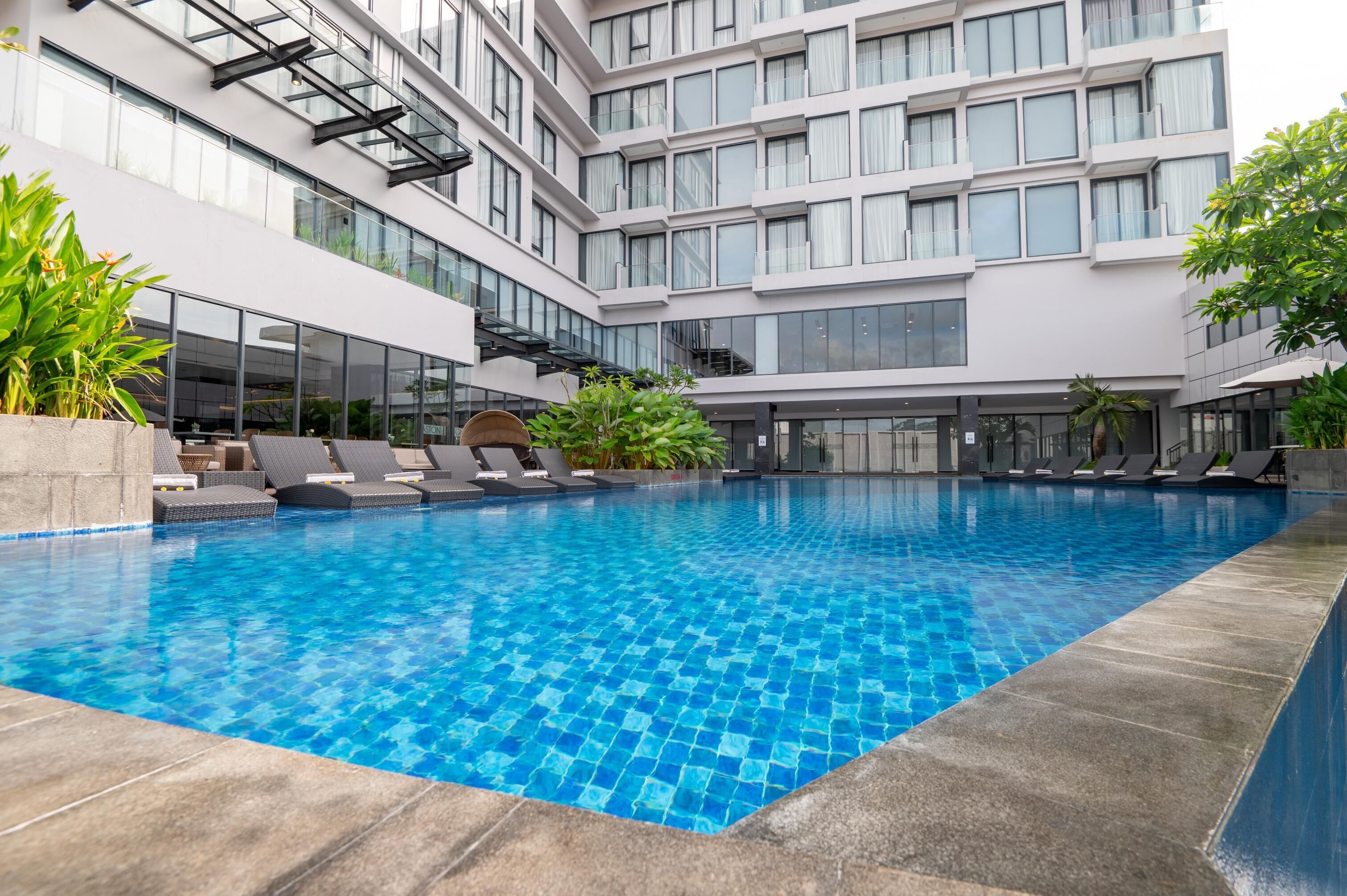Ein modernes Hotel mit großem Innenpool, mehreren Stockwerken und einer Glasfassade.