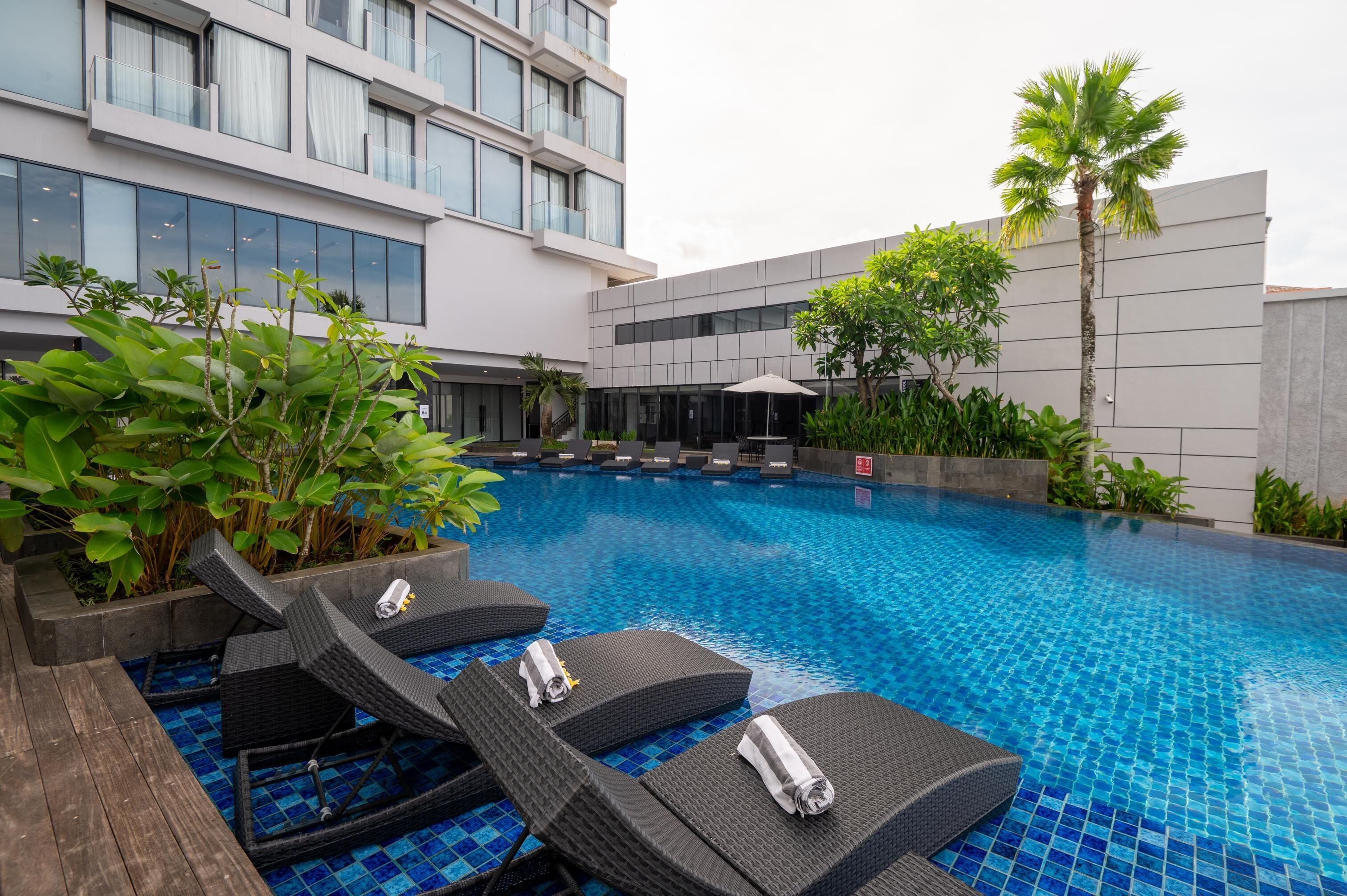 A modern hotel pool area with lounge chairs and a clear blue pool.