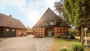 A traditional half-timbered house with a paved driveway and a small garden area. - In Idyllischer Wohnlage auf Einem Fachwerkhof in der Natur (Ladbergen)