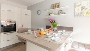 A modern kitchen with white cabinets, a built-in oven, and a breakfast setup on the island. - In Idyllischer Wohnlage auf Einem Fachwerkhof in der Natur (Ladbergen)