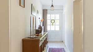 A hallway with a wooden console table, a patterned rug, and a window with curtains. - In Idyllischer Wohnlage auf Einem Fachwerkhof in der Natur (Ladbergen)