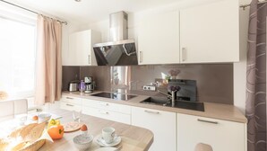 A modern kitchen with white cabinets, a stainless steel range hood, and a wooden countertop. - In Idyllischer Wohnlage auf Einem Fachwerkhof in der Natur (Ladbergen)