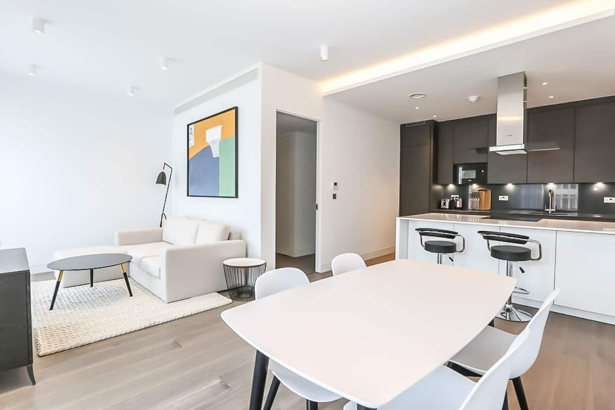 A modern apartment with a dining area, a kitchen, and a living room.
