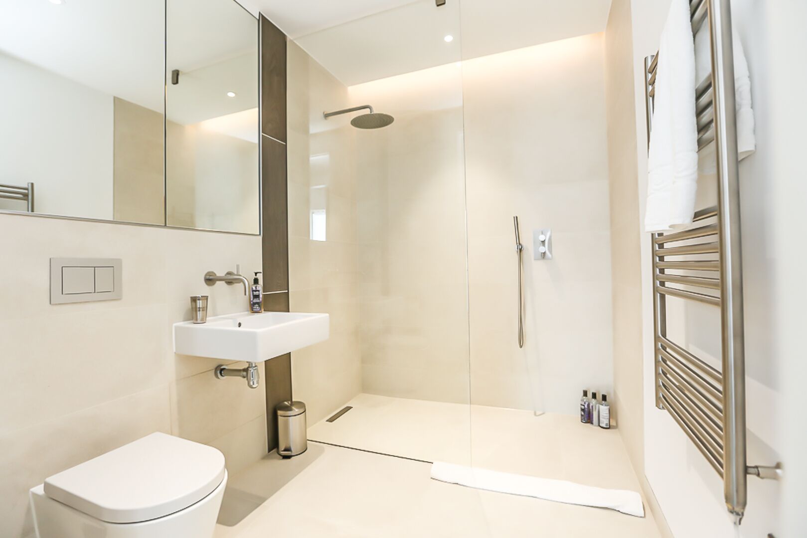 A modern bathroom with a toilet, sink, and walk-in shower.