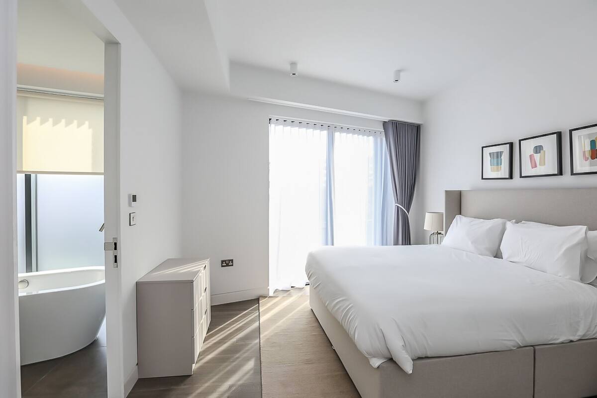 A modern hotel room with a large bed, a desk, and a window with curtains.