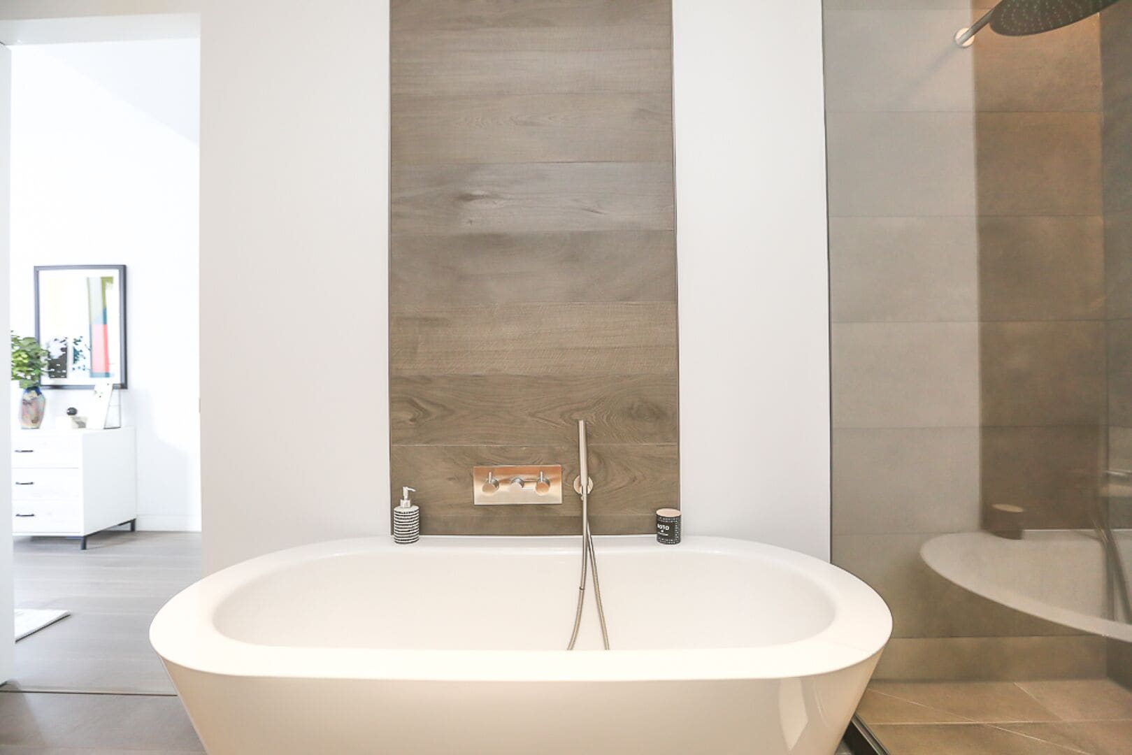 A modern bathroom with a freestanding bathtub, a wooden accent wall, and a glass shower enclosure.