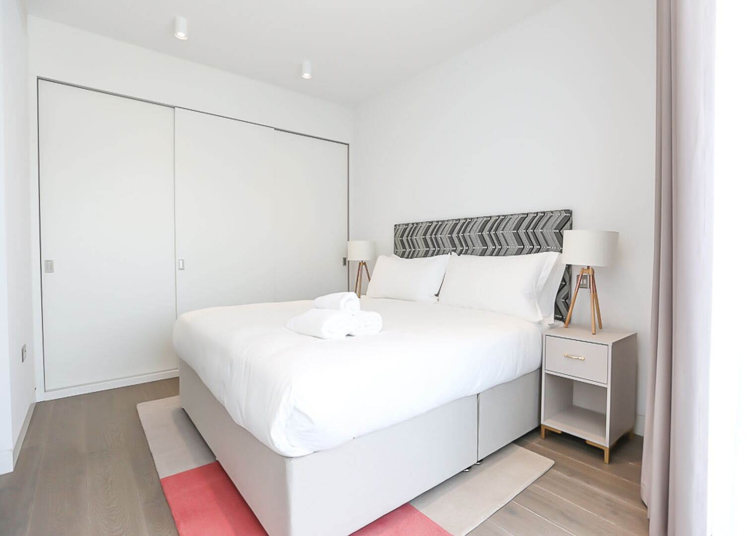 Une chambre à coucher moderne avec un grand lit, des tables de chevet et une armoire.