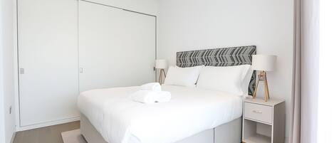 Une chambre à coucher moderne avec un grand lit, des tables de chevet et une armoire.