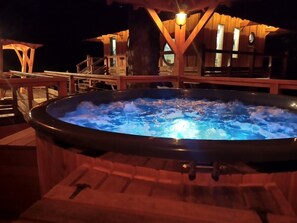 Relax in the hot tub on the deck, surrounded by a covered structure with a staircase.