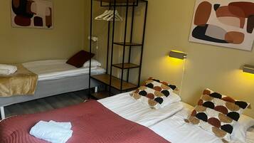 A hotel room with two beds, a wardrobe, abstract wall art, and a bedside lamp.