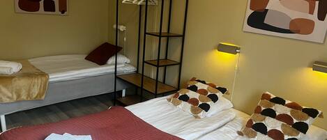 Een hotelkamer met twee bedden, een kledingkast, abstracte wanddecoratie en een bedlampje.
