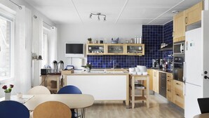 A modern kitchen with a central island, wooden cabinets, a built-in oven, and a blue-tiled backsplash.