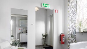 A modern hotel lobby with a reception desk, a seating area, a kitchenette, and a fire extinguisher.