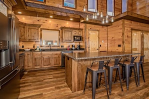 Una cocina estilo cabaña de madera con una isla central, taburetes de bar y electrodomésticos modernos.
