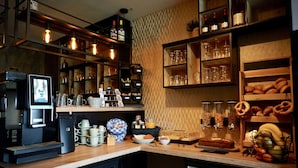 A kitchen with a coffee machine, shelves with glassware, and a bread display. - Gasthaus Paula App. C (Üdersdorf)