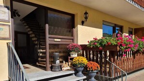 A hotel entrance with a wooden staircase, a welcome sign, and flower planters. - Gasthaus Paula App. C (Üdersdorf)
