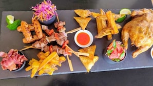 A variety of grilled meats and vegetables on a slate board, accompanied by dipping sauces and lime wedges. - Cosy homes ltd (Mlolongo)