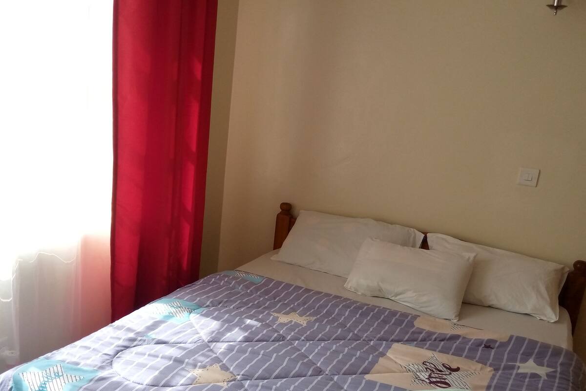 Una cama con una colcha a rayas, almohadas blancas y una toalla verde.