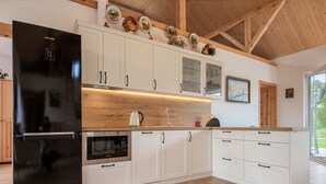 A modern kitchen with white cabinetry, a black refrigerator, a built-in oven, and a wooden countertop. - Zagroda nad Krutynią by Interhome (Spychowo-Kierwik)