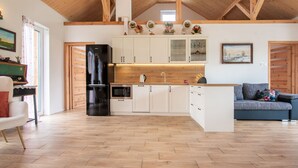 A spacious kitchen with wooden beams, white cabinets, and a black refrigerator. - Zagroda nad Krutynią by Interhome (Spychowo-Kierwik)