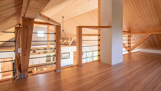 A spacious attic room with wooden beams, a sloped ceiling, and a view of the lower level. - Zagroda nad Krutynią by Interhome (Spychowo-Kierwik)
