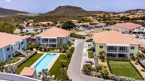 Un barrio residencial con casas, una piscina y una montaña al fondo.
