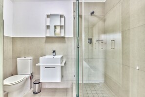 A modern bathroom with a toilet, sink, and glass-enclosed shower.