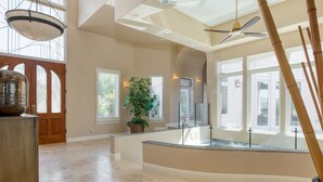 A spacious interior with a high ceiling, large windows, and a central potted plant.