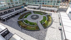 A modern building with a circular plaza, benches, and a fountain.