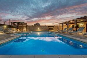 Une piscine avec des chaises longues et un mur en pierre.