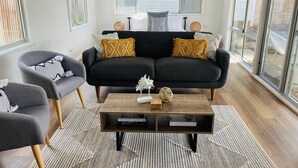 Un salon moderne avec un canapé noir, deux fauteuils et une table basse en bois.