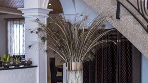 A glass table with an elephant base, surrounded by decorative peacock feathers in a metallic vase. - The Haven Boutique Hotel - Kumasi, Ghana (Ejisu)