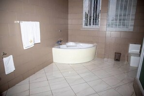 A bathroom with a large bathtub, a toilet, and a sink. - The Haven Boutique Hotel - Kumasi, Ghana (Ejisu)