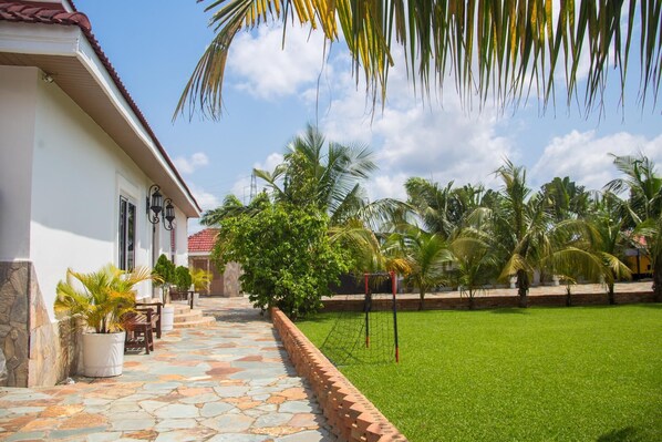 A courtyard with a stone pathway leading to a house with a red-tiled roof. - The Haven Boutique Hotel - Kumasi, Ghana (Ejisu)