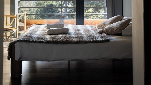 A bedroom with a large window, wooden beams, a bed with a fluffy blanket, and a view of trees and mountains. - Vaste et Prestigieux Chalet à Font Romeu Pyrénées 2000 (Bolquère)