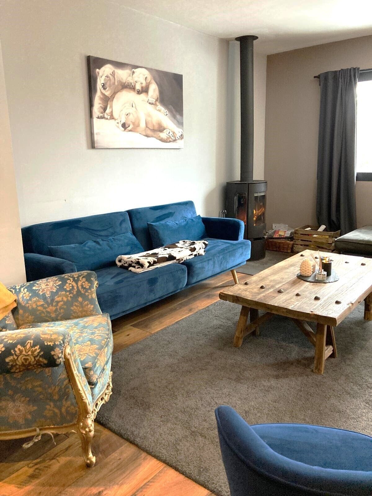 Un saló amb un sofà blau, una taula de centre de fusta i un armari amb dibuixos. Hi ha un quadre de pols polar a la paret.