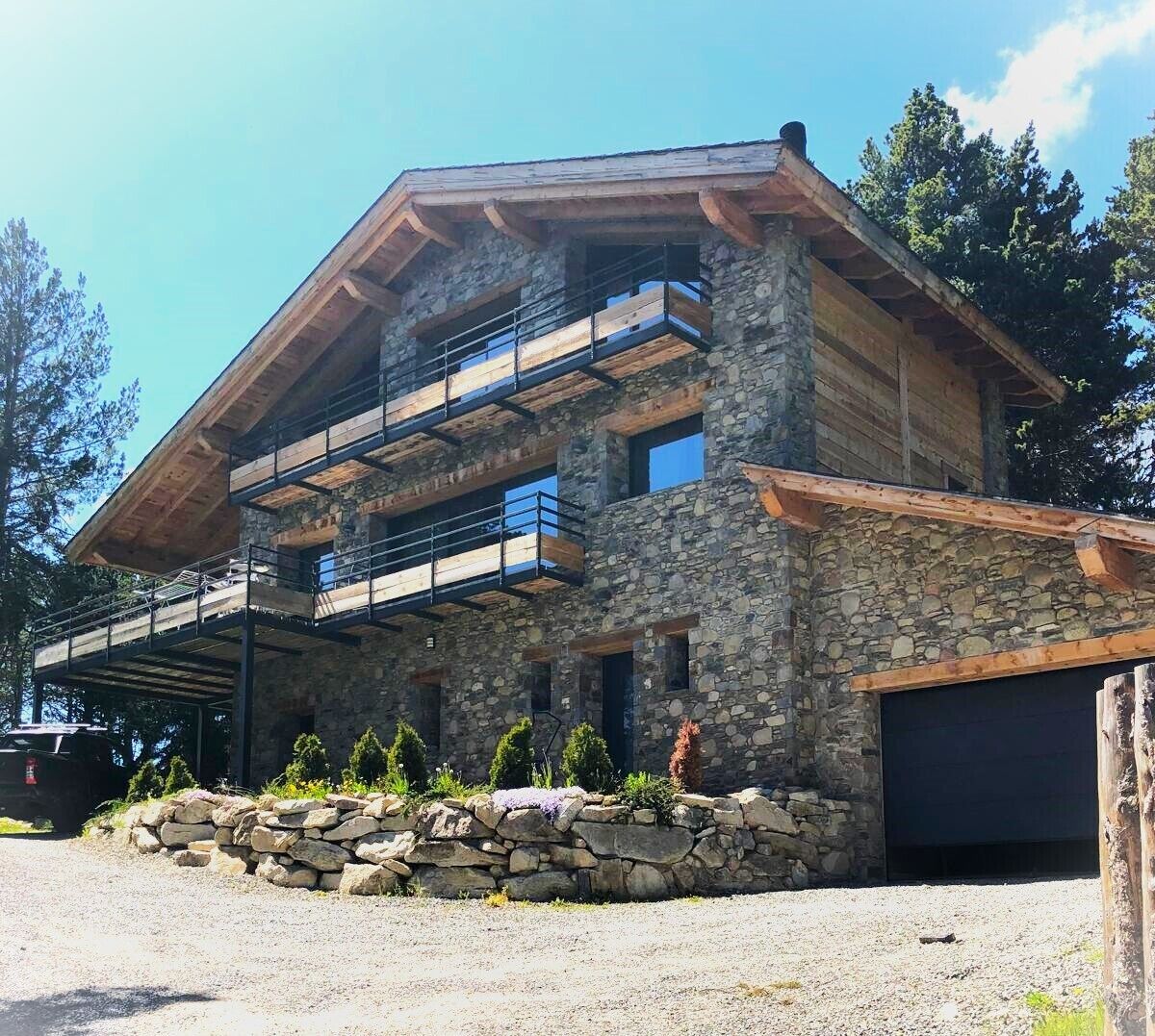 A two-story stone building with a wooden balcony and a garage.