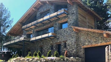 A two-story stone building with a wooden balcony and a garage.