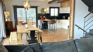 A modern living space with a leather sofa, dining area, kitchen, and staircase. - Vaste et Prestigieux Chalet à Font Romeu Pyrénées 2000 (Bolquère)