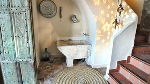 A rustic bathroom with a stone sink, a wooden door, and a stone floor. - THE BALCONY OF THE OLIVE TREES (Luque)