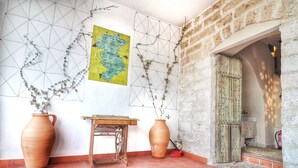 A room with a tiled floor, a wooden table, two large vases with plants, a map on the wall, and a rustic wooden door. - THE BALCONY OF THE OLIVE TREES (Luque)