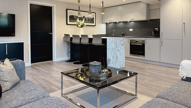 A modern living room with a glass coffee table, grey sofas, and a TV mounted on the wall. - Impeccable Farm Apartment in Walberton, England (Arundel)