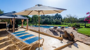 A poolside area with lounge chairs, a covered seating area, and a stone pathway. - Pet-Friendly "Finca Pep" with Pool & Wi-Fi (Sineu)