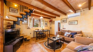 A living room with a TV, sofa, coffee table, and a dining area with chairs and a table. - Pet-Friendly "Finca Pep" with Pool & Wi-Fi (Sineu)