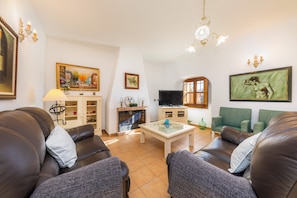 Una sala de estar con chimenea, televisor y dos sillones verdes.